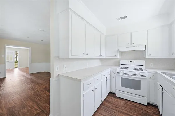a kitchen with cabinets appliances and wooden floor