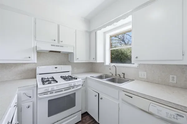 a kitchen with cabinets appliances a sink and a window