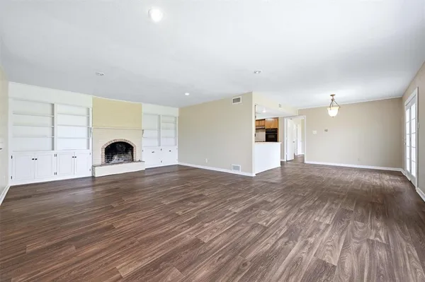 a view of empty room with wooden floor and window