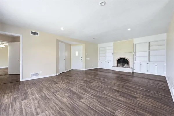 a view of empty room with a fireplace and wooden floor