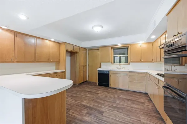 a large kitchen with stainless steel appliances granite countertop a sink dishwasher a stove and a refrigerator with wooden floor