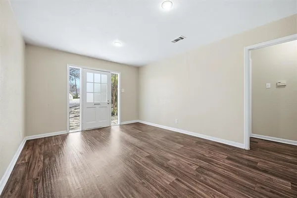 a view of an empty room with wooden floor and a window