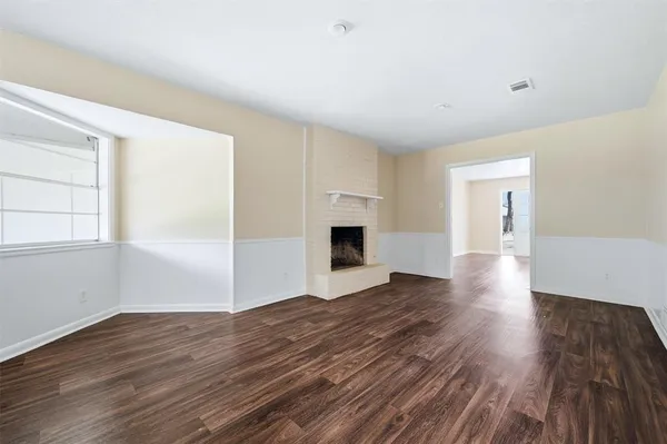 a view of empty room with wooden floor and fireplace