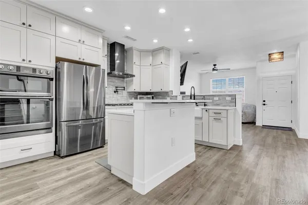 a kitchen with stainless steel appliances granite countertop a refrigerator a stove a sink and white cabinets