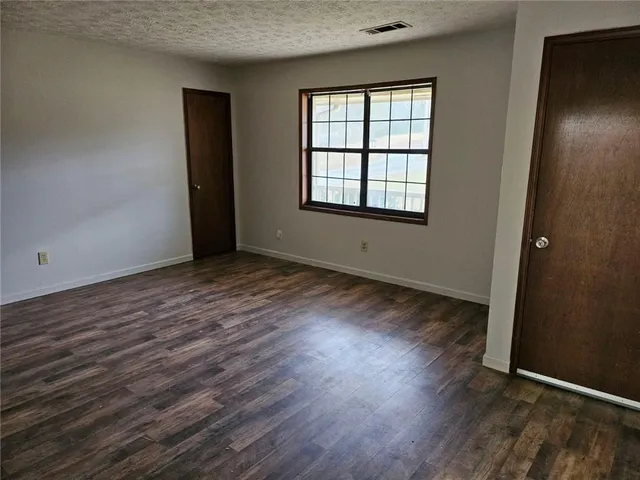 an empty room with wooden floor and windows