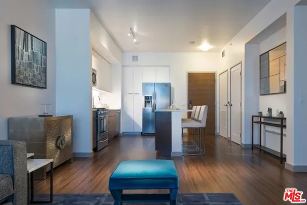 a living room with stainless steel appliances furniture and a wooden floor