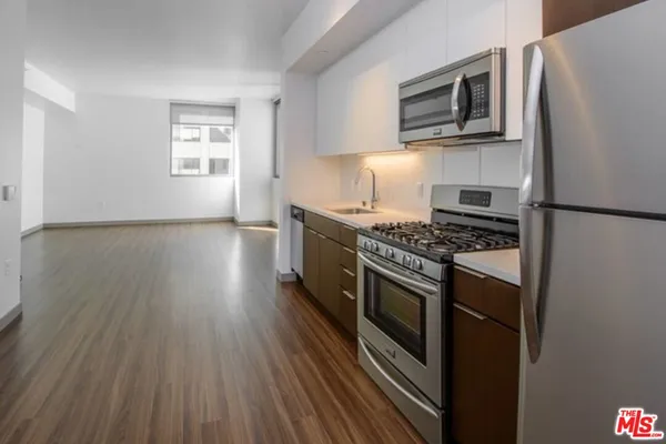 a kitchen with stainless steel appliances a stove a microwave and a hard wood floors