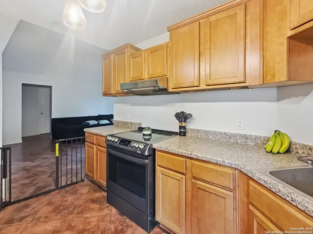 a kitchen with granite countertop a sink a stove and cabinets