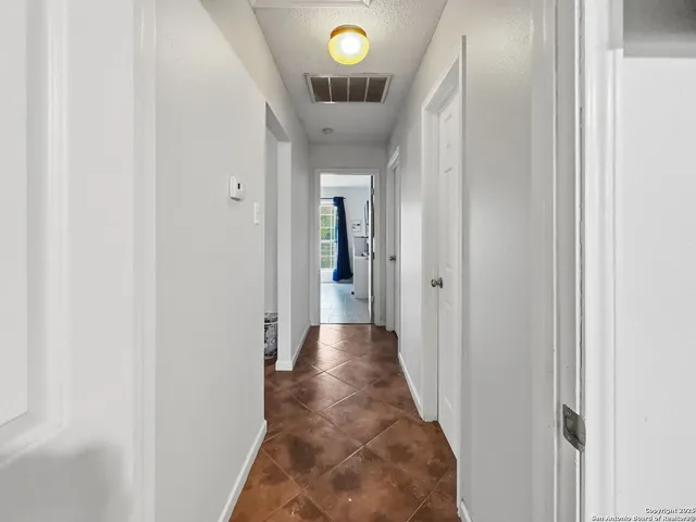 a view of a hallway with wooden floor and a chandelier