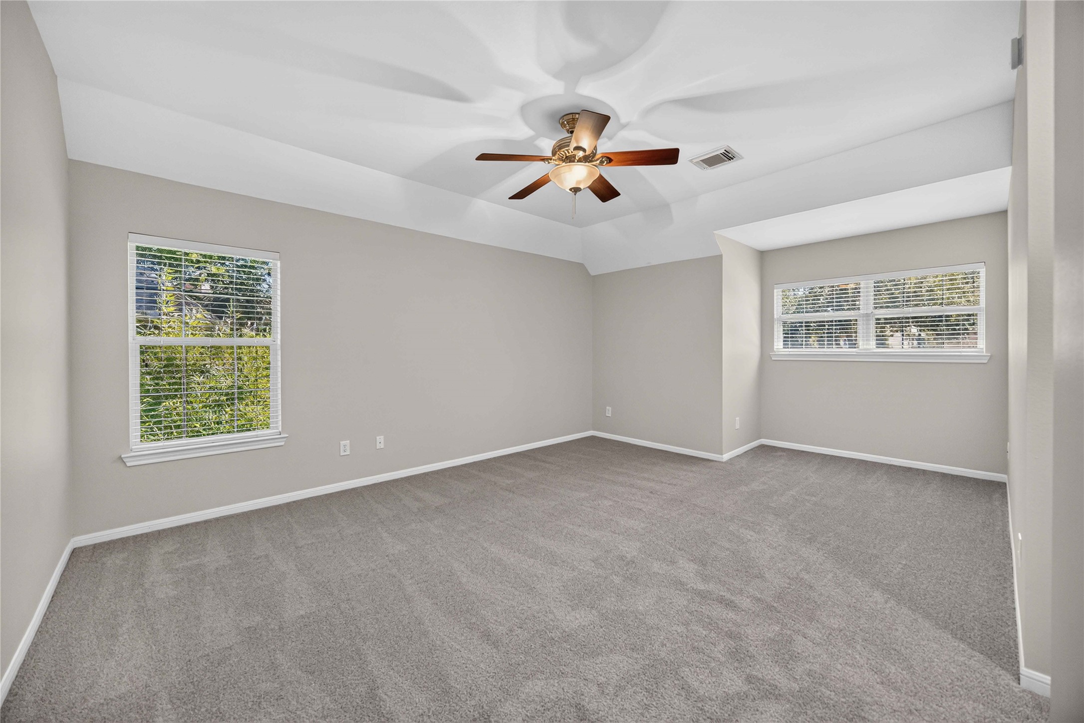 3303 Raleigh Row Missouri City, TX 77459 - Photo 40 of 50 Spacious Large Secondary bedroom with plush carpeting, neutral walls, and abundant natural light from two large windows, complemented by a stylish ceiling fan.