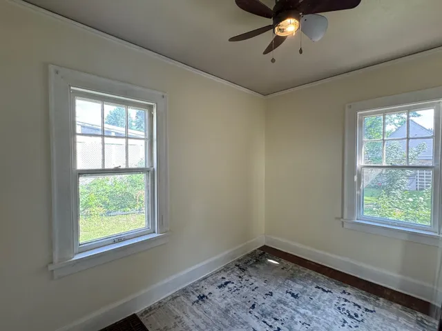 a view of an empty room with a window and wooden floor