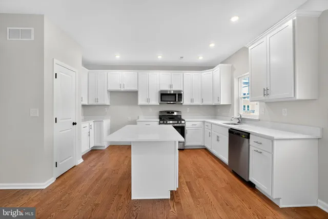 a kitchen with white cabinets stainless steel appliances and a center island