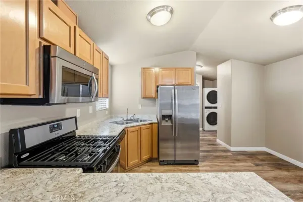 a kitchen with stainless steel appliances granite countertop a refrigerator a stove and a sink with wooden cabinets