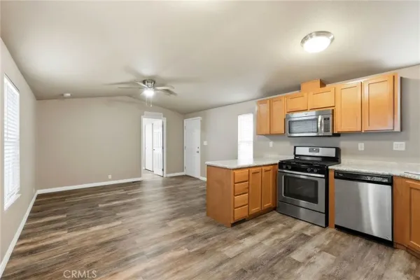 a kitchen with stainless steel appliances granite countertop a sink a stove a refrigerator with grey cabinets