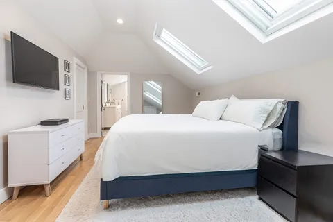 a spacious bedroom with a bed and a flat tv screen on wall