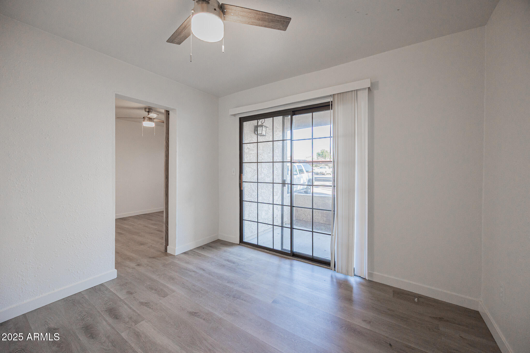 3131 West Cochise Drive, Unit 129 Phoenix, AZ 85051 - Photo 12 of 17 an empty room with wooden floor chandelier and windows
