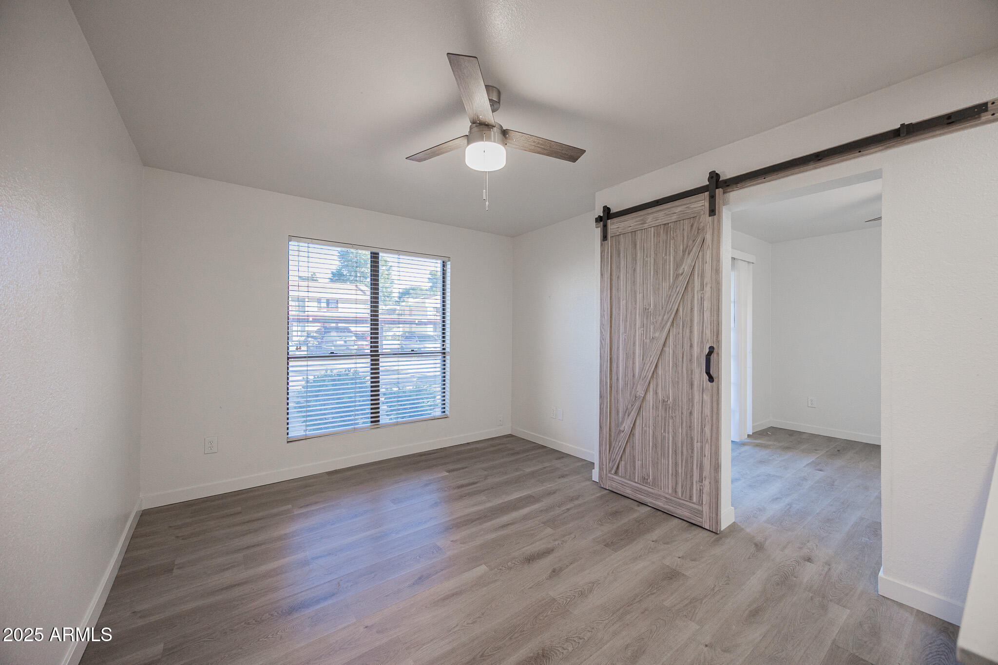 3131 West Cochise Drive, Unit 129 Phoenix, AZ 85051 - Photo 4 of 17 a view of an empty room with wooden floor and a window