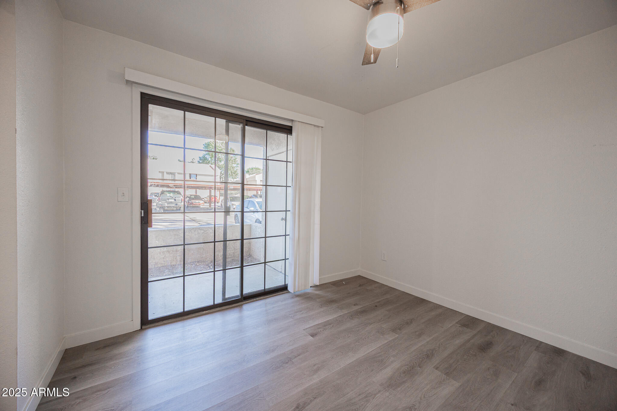 3131 West Cochise Drive, Unit 129 Phoenix, AZ 85051 - Photo 10 of 17 an empty room with wooden floor and windows