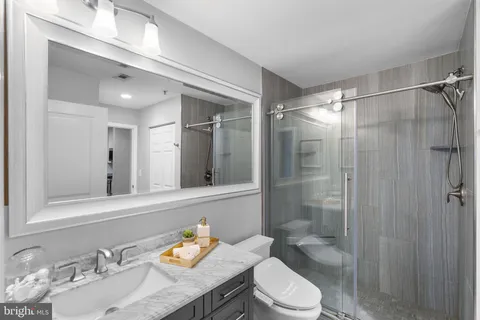 a bathroom with a granite countertop sink toilet a mirror and shower