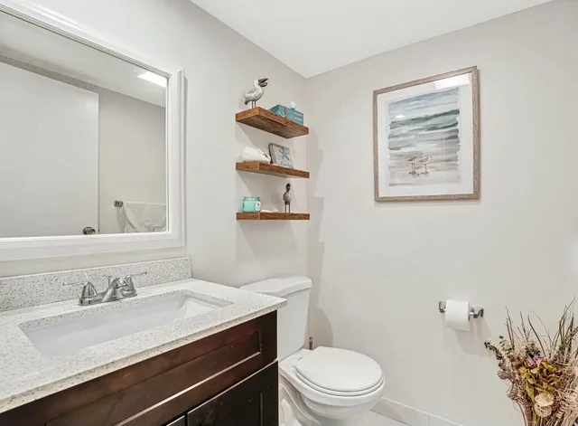 a bathroom with a granite countertop sink mirror vanity and toilet