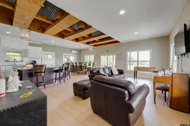 a living room with furniture kitchen view and a wooden floor