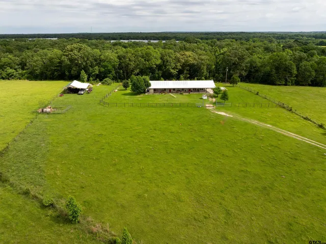 a view of a lake with lawn chairs and large trees