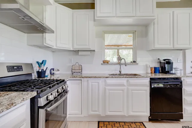 a kitchen with granite countertop a stove sink and cabinets