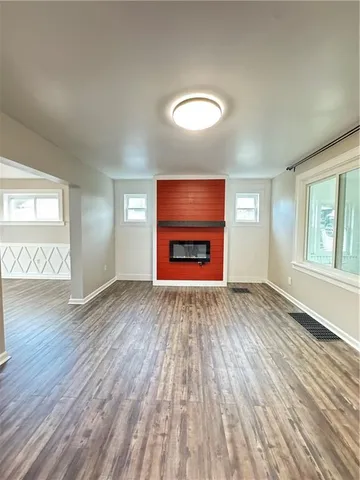 an empty room with wooden floor cabinet and windows