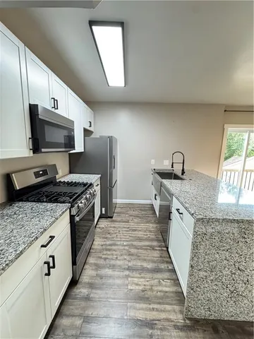 a large kitchen with granite countertop a sink and a stove top oven with wooden floor