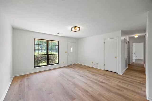 a view of an empty room with wooden floor and a window