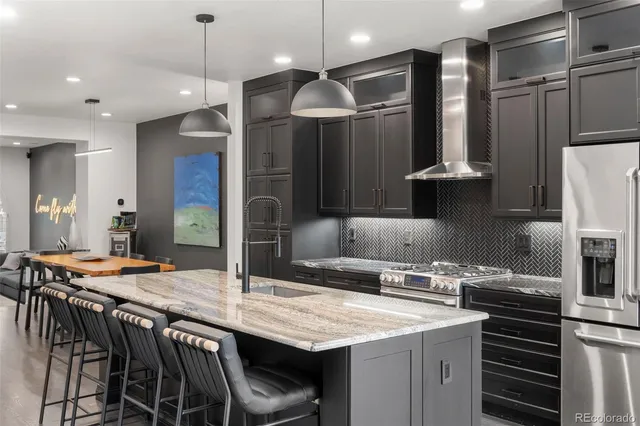 a kitchen with stainless steel appliances kitchen island a table chairs in it and wooden floors