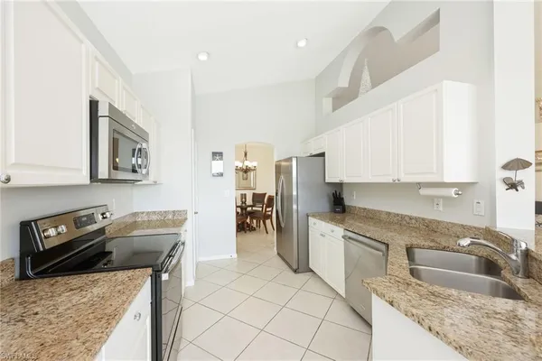 a kitchen with granite countertop a sink a stove top oven and cabinets