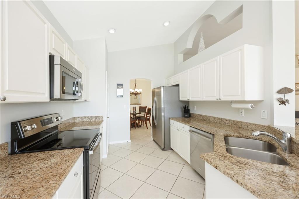 7828 Gardner Drive, Unit 5202 Naples, FL 34109 - Photo 11 of 44 a kitchen with granite countertop a sink a stove top oven and cabinets