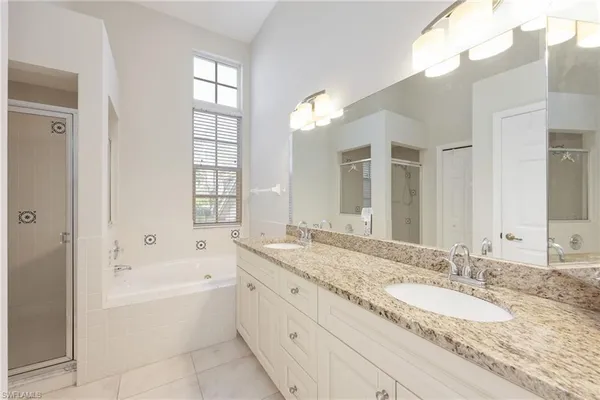 a bathroom with a granite countertop tub a double vanity sink and a large mirror