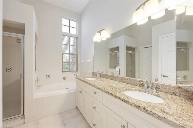 a bathroom with a granite countertop tub a double vanity sink and a large mirror