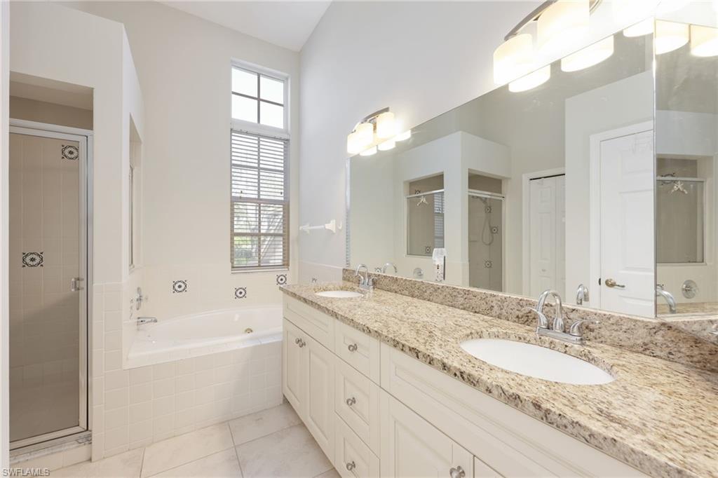 7828 Gardner Drive, Unit 5202 Naples, FL 34109 - Photo 19 of 44 a bathroom with a granite countertop tub a double vanity sink and a large mirror