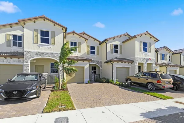 a front view of a house with cars parked