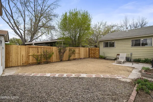 a backyard of a house with large trees and outdoor seating