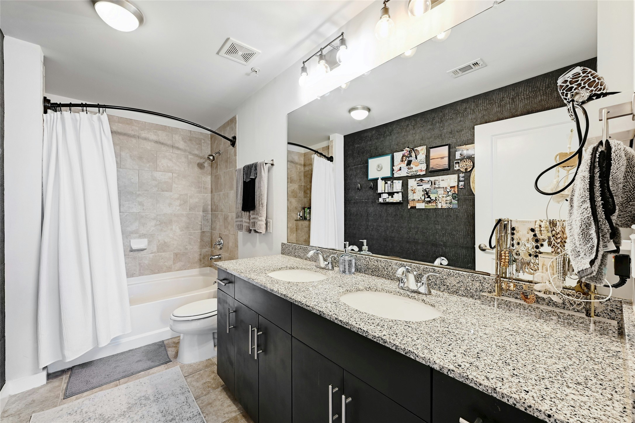 360 Nueces Street, Unit 1809 Austin, TX 78701 - Photo 16 of 25 Bathroom featuring a dual-sink vanity with a granite countertop, dark wood-finish cabinetry, and a full-width mirror