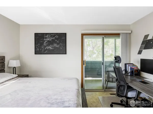 a bedroom with a bed painting on wall and a large window