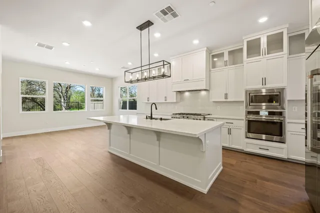 a kitchen with white cabinets and wooden floor
