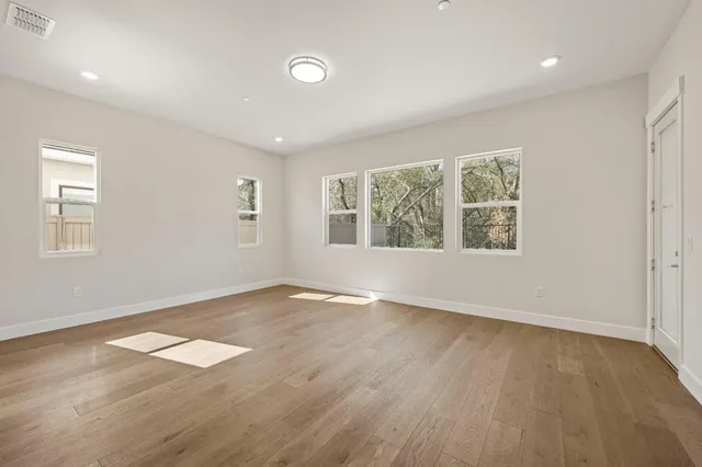 an empty room with wooden floor and windows