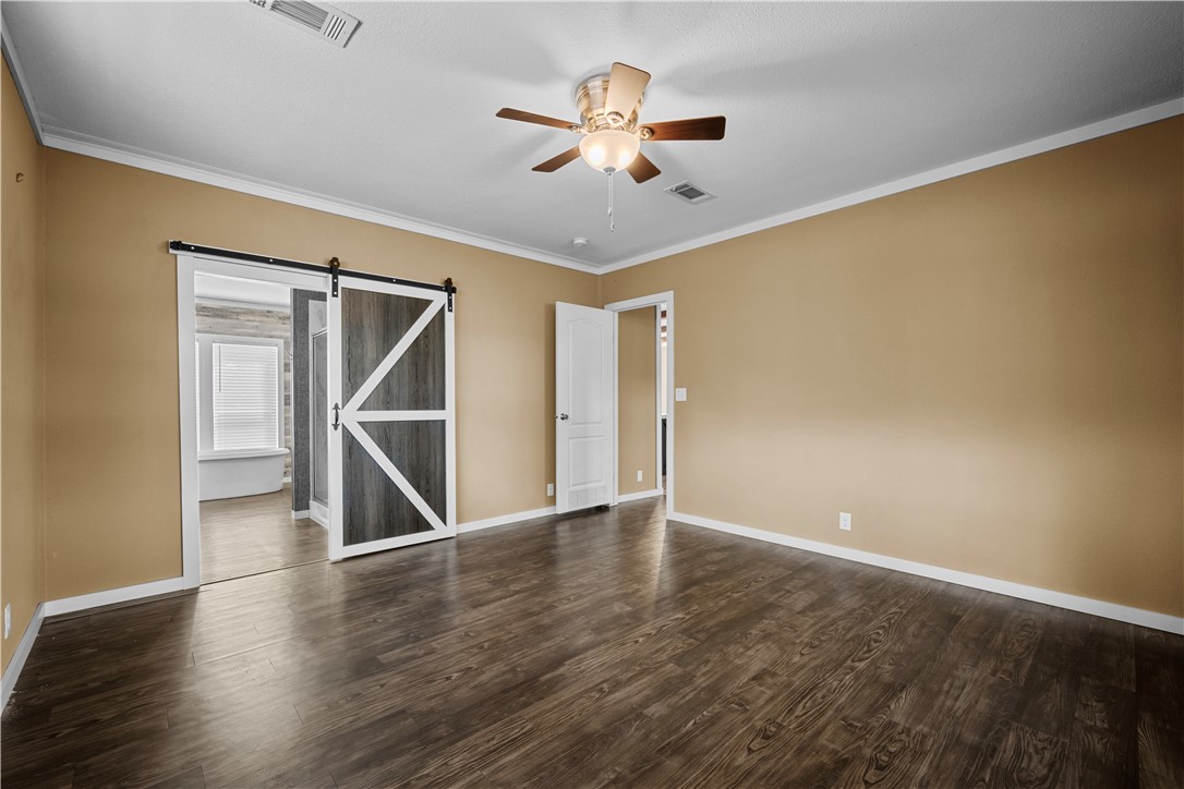 1511 Monkey Road Rockport, TX 78382 - Photo 22 of 40 a view of an empty room with wooden floor and a ceiling fan