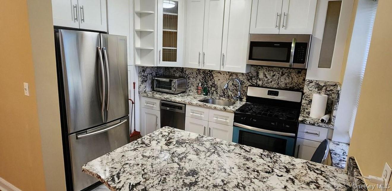 141-39 79th Avenue, Unit 3O Queens, NY 11367 - Photo 3 of 10 a kitchen with granite countertop a refrigerator stove and microwave