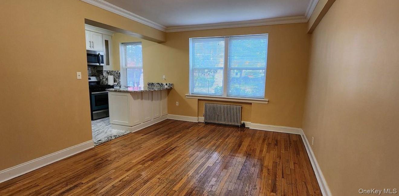 141-39 79th Avenue, Unit 3O Queens, NY 11367 - Photo 4 of 10 an empty room with wooden floor and windows