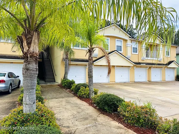 a view of a white house next to a road and yard