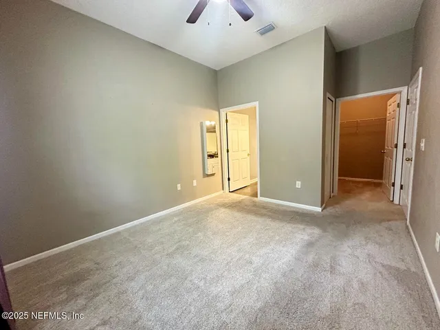 an empty room with chandelier fan and windows