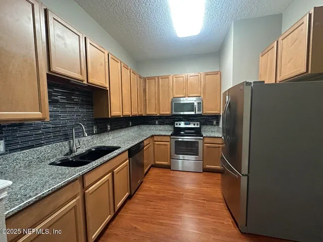a kitchen with granite countertop stainless steel appliances a refrigerator sink and microwave