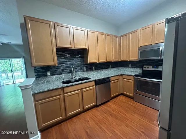 a kitchen with stainless steel appliances granite countertop a stove a sink and a microwave