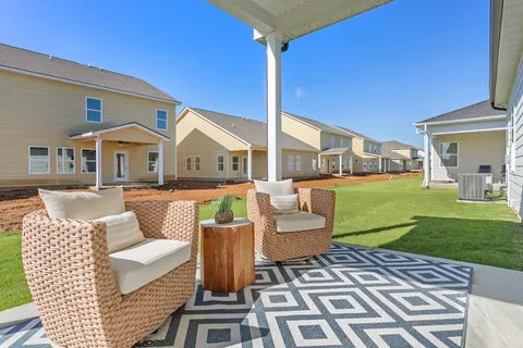a backyard of a house with lawn chairs and a yard